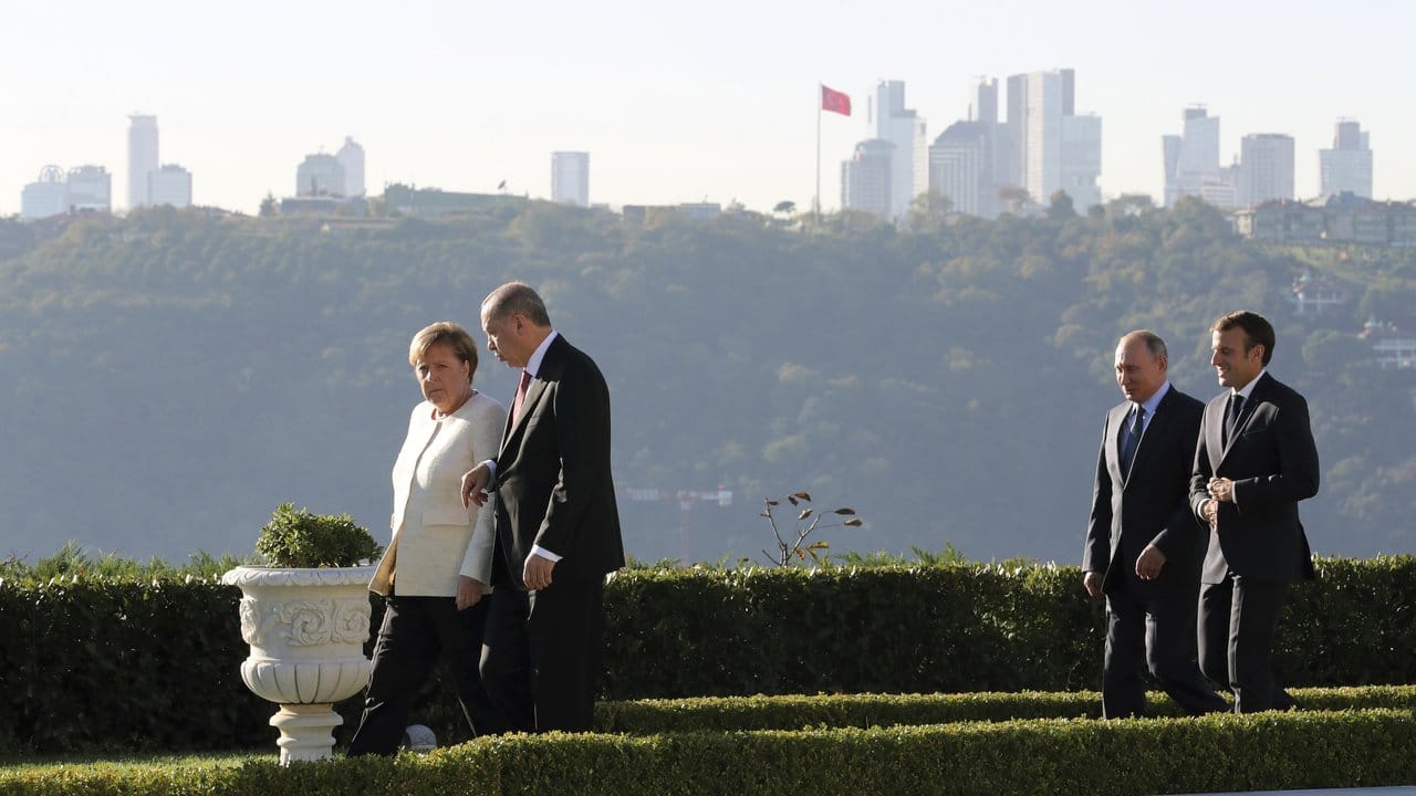 Bundeskanzlerin Angela Merkel im Gespräch mit Recep Tayyip Erdogan dahinter Putin und Macron während eines Spaziergangs vor dem Vierer-Gipfel zur Zukunft Syriens.