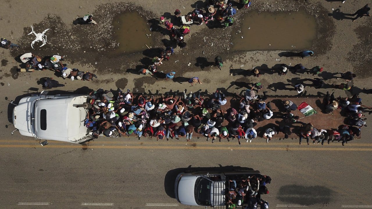 Migranten klettern auf den Anhänger eines Lastwagens, während eine Karawane von Menschen ihren langsamen Marsch zur US-Grenze fortsetzt. Migranten klettern auf den Anhänger eines Lastwagens, während eine Karawane von Menschen ihren langsamen Marsch zur US-Grenze fortsetzt.