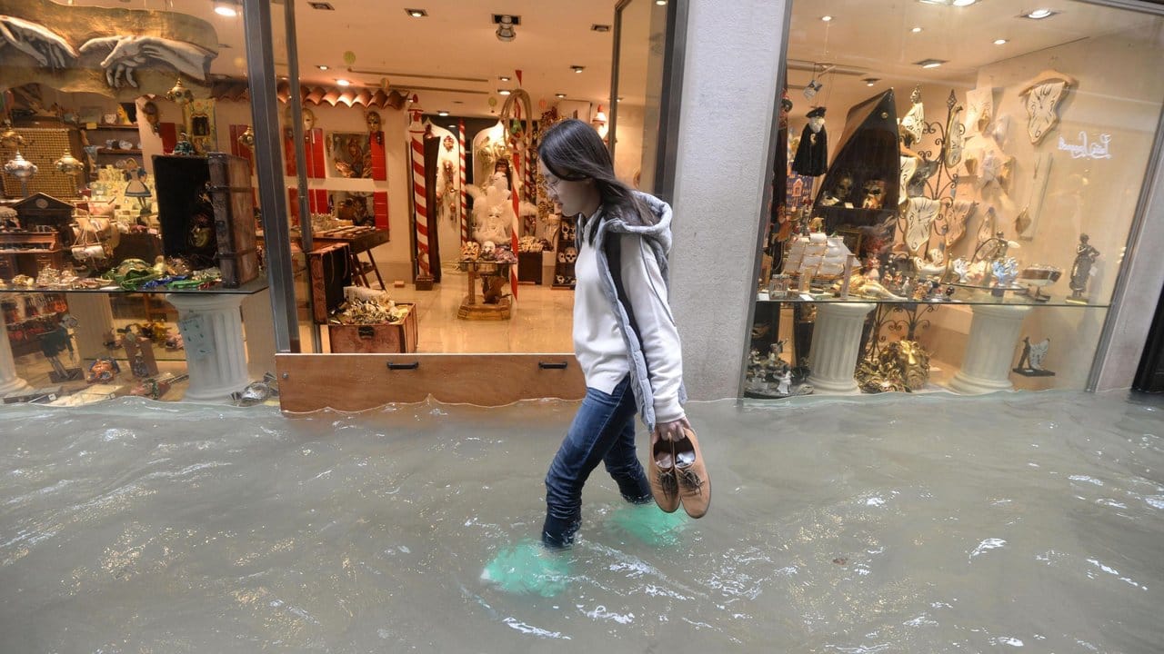 Eine Frau watet am Montag in Venedig durch das Wasser einer überfluteten Straße.