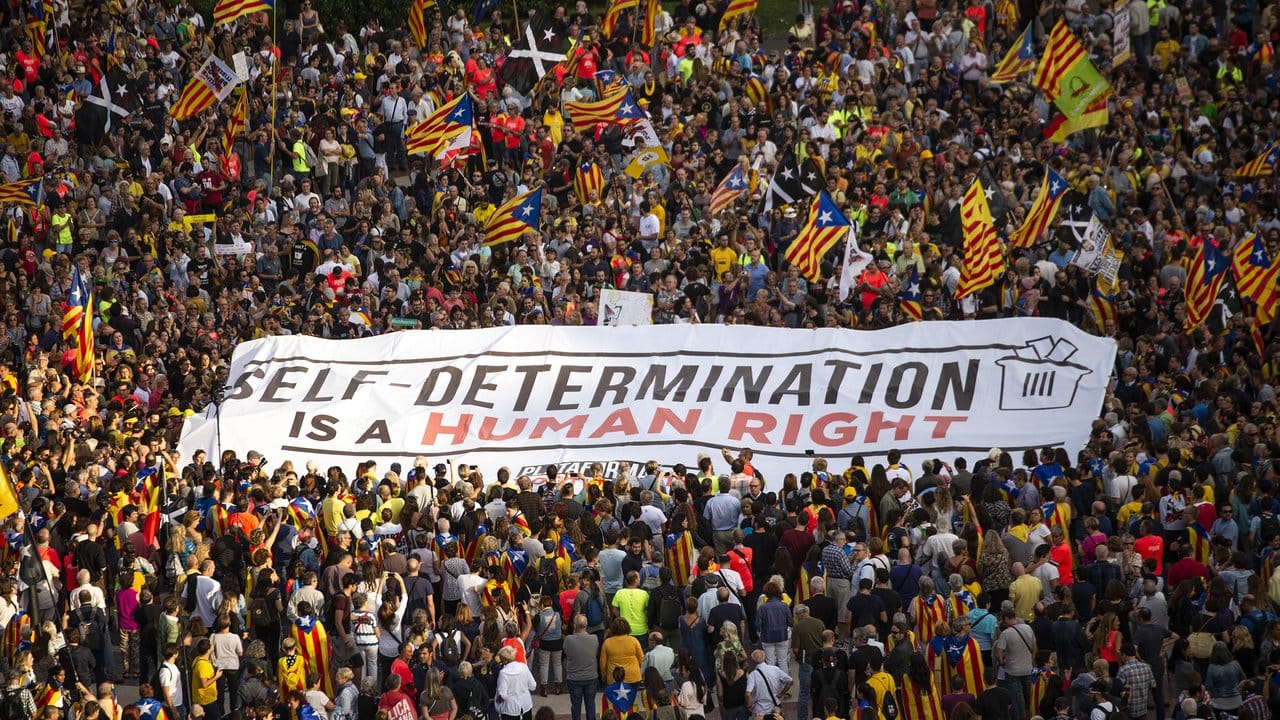 Tausende Menschen marschieren mit einem Banner "Selbstbestimmung ist ein Menschenrecht" zum Parlament von Katalonien.