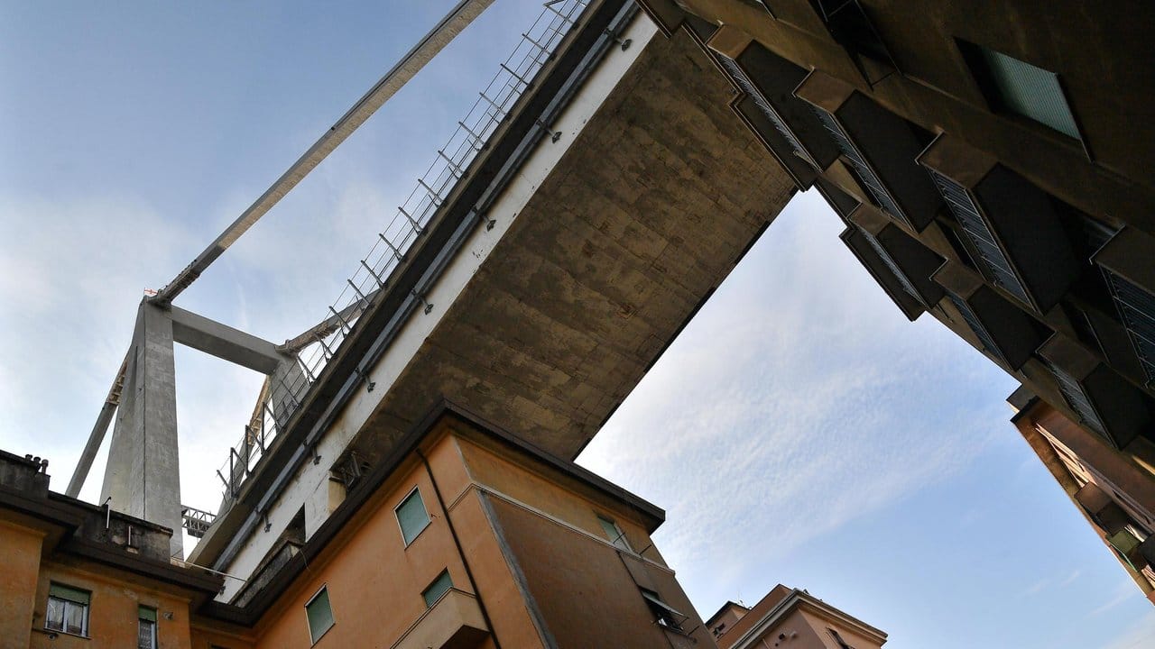 Ein Teil der eingestürzten Morandi-Brücke hängt bedrohlich über evakuierten Wohnhäusern.