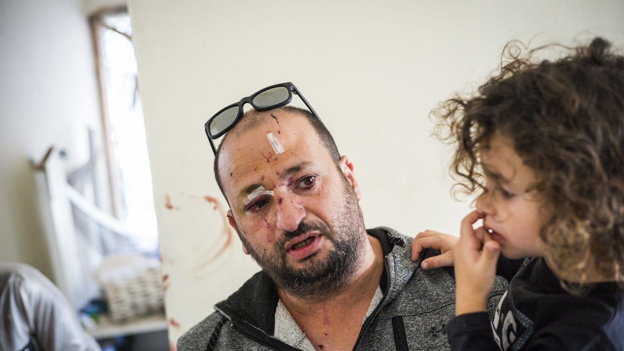 Ein verletzter Israeli trägt sein Kind auf dem Arm, während er in seiner beschädigten Wohnung steht, die von einer Rakete aus dem Gazastreifen getroffen wurde.