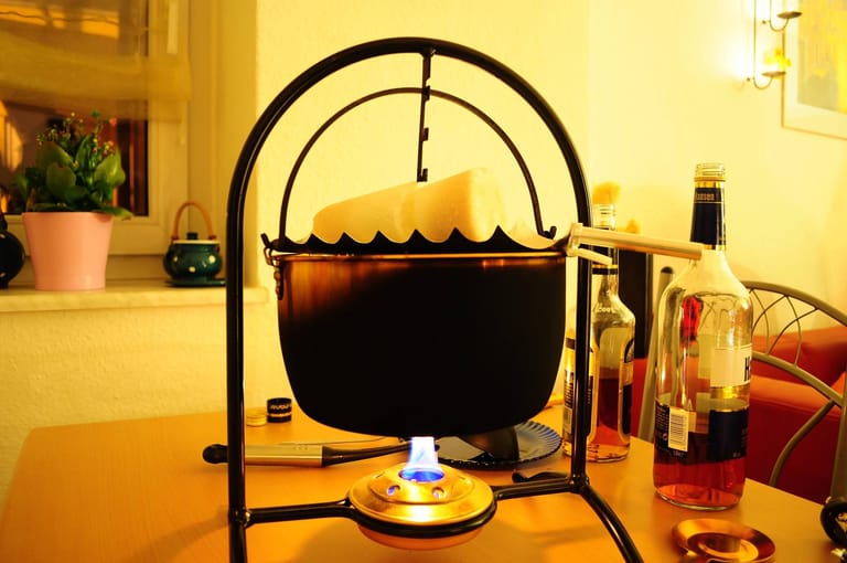 Wenn der Punsch heiß ist, wird eine Feuerzange oder Metallreibe über dem Topf platziert und der Zuckerhut daraufgestellt.