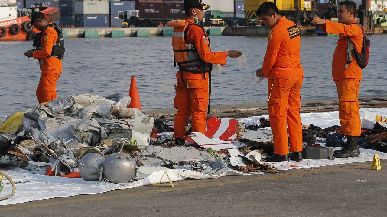 Mitarbeiter der indonesischen Such- und Rettungsbehörde inspizieren Trümmerteile.