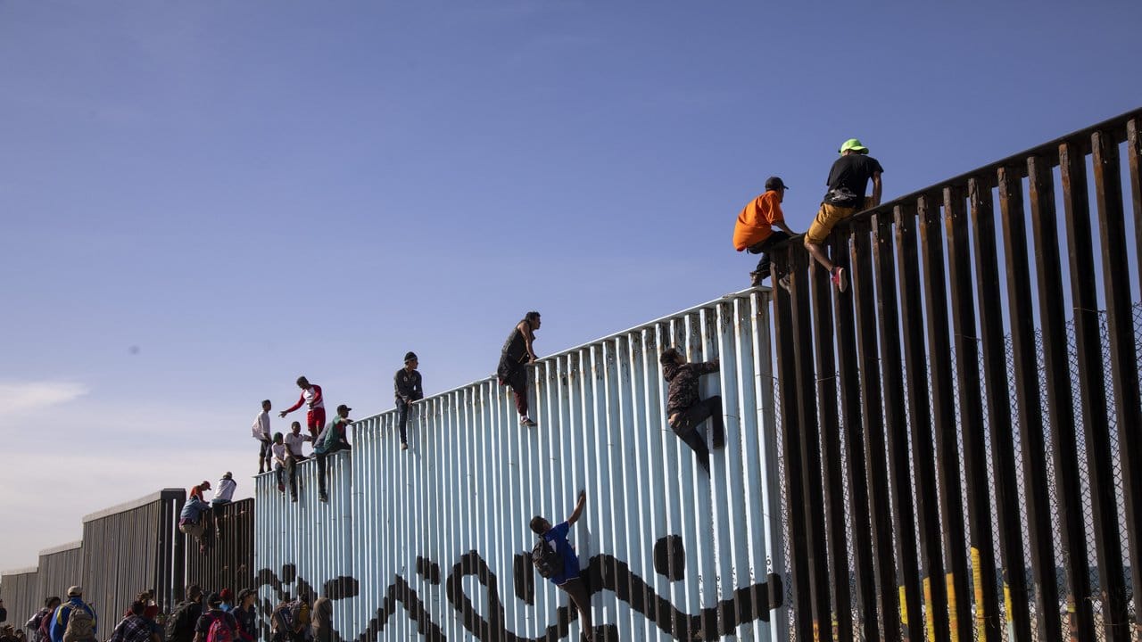 Flüchtlinge sitzen bei Tijuana auf dem Grenzzaun zwischen Mexiko und den USA.