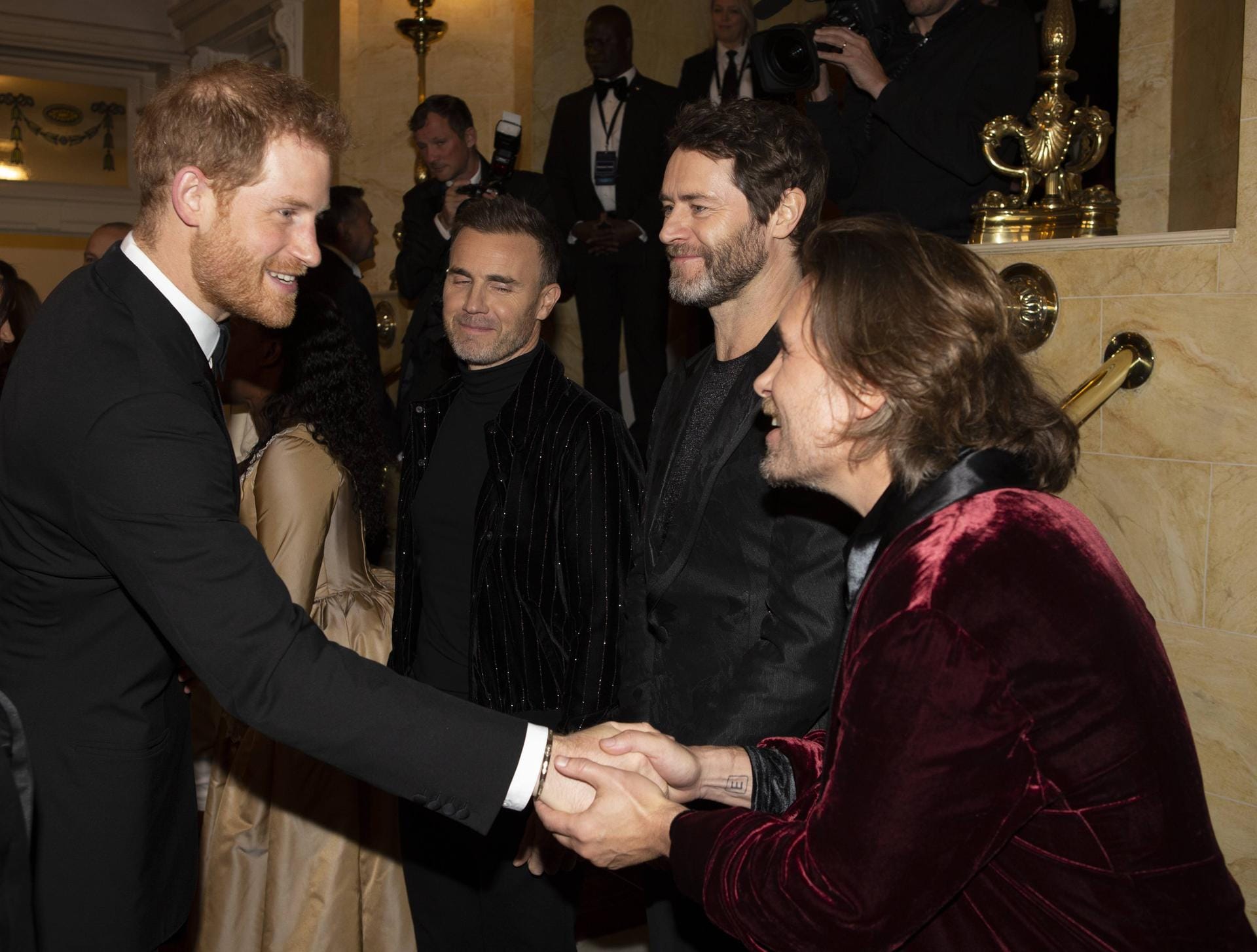 Take That: Prinz Harry schüttelte Mark Owen die Hand, seine Bandkollegen grinsen zufrieden.