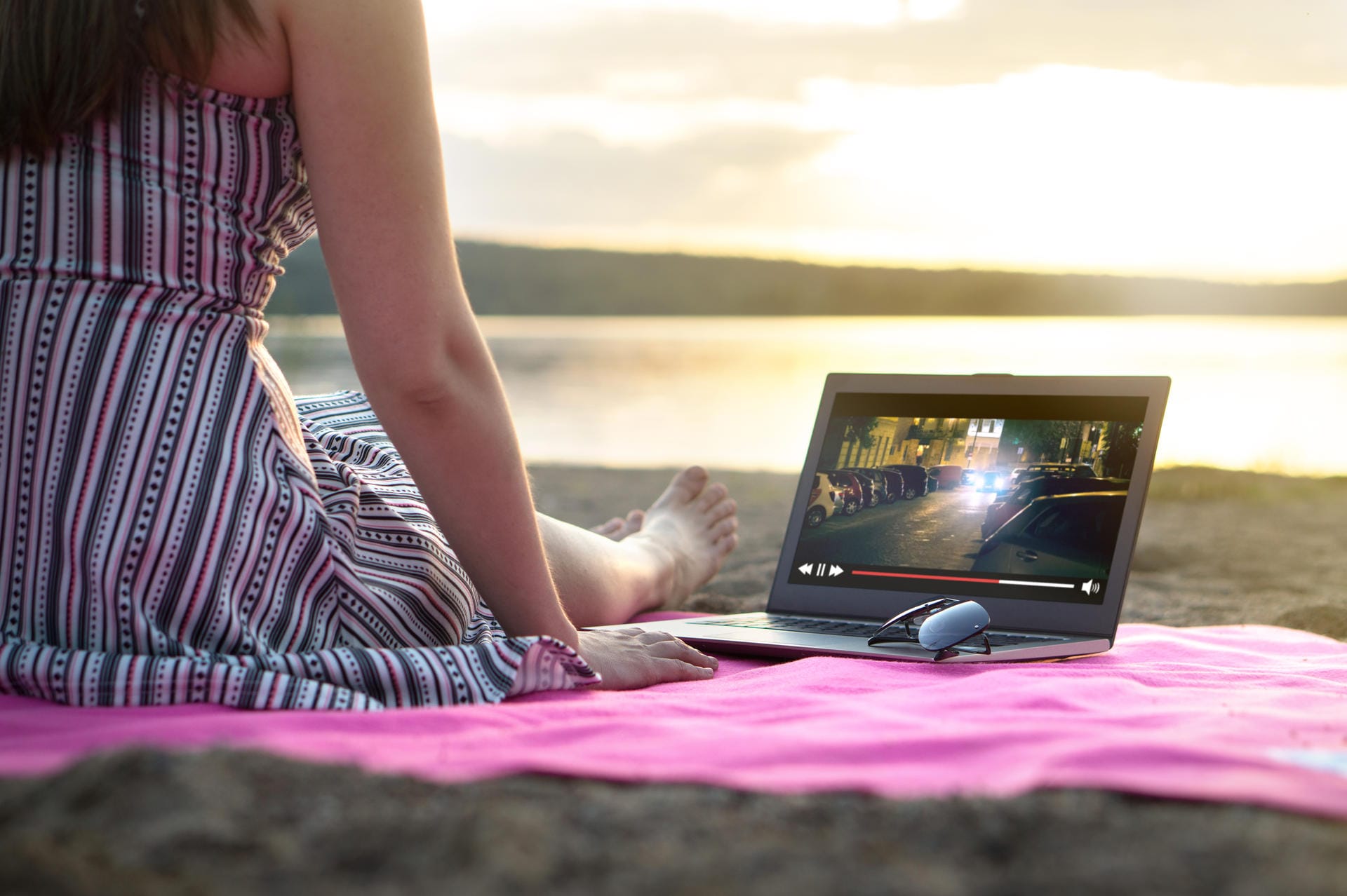 Eine Frau am Strand nutzt Video-Streaming auf dem Laptop: Immer mehr Windows 10-Rechner unterstützen Video-Streaming in HDR-Qualität.