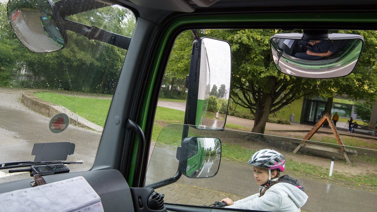 Eine Schülerin hält mit ihrem Fahrrad neben einem LKW, der mit vier Außenspiegeln auf der Beifahrerseite ausgestattet ist.