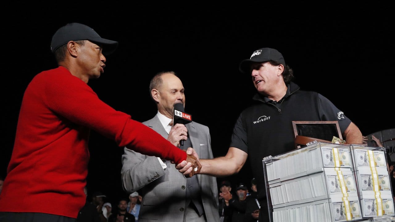 Neben einem Haufen Banknoten reicht Sieger Phil Mickelson (r) Tiger Woods (l) die Hand.