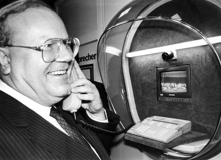 Die Verständigung per Ton und Bild probt Bundeswirtschaftsminister Martin Bangemann (FDP) in einer Bildtelefonzelle bei seinem Eröffnungsrundgang über die CeBIT 1986. Die von der Firma Sony erstmals vorgestellte Sprechkabine enthält neben dem Telefon einen kleinen Bildschirm und eine Kamera.