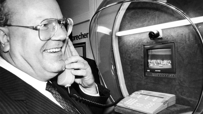 Die Verständigung per Ton und Bild probt Bundeswirtschaftsminister Martin Bangemann (FDP) in einer Bildtelefonzelle bei seinem Eröffnungsrundgang über die CeBIT 1986. Die von der Firma Sony erstmals vorgestellte Sprechkabine enthält neben dem Telefon einen kleinen Bildschirm und eine Kamera.