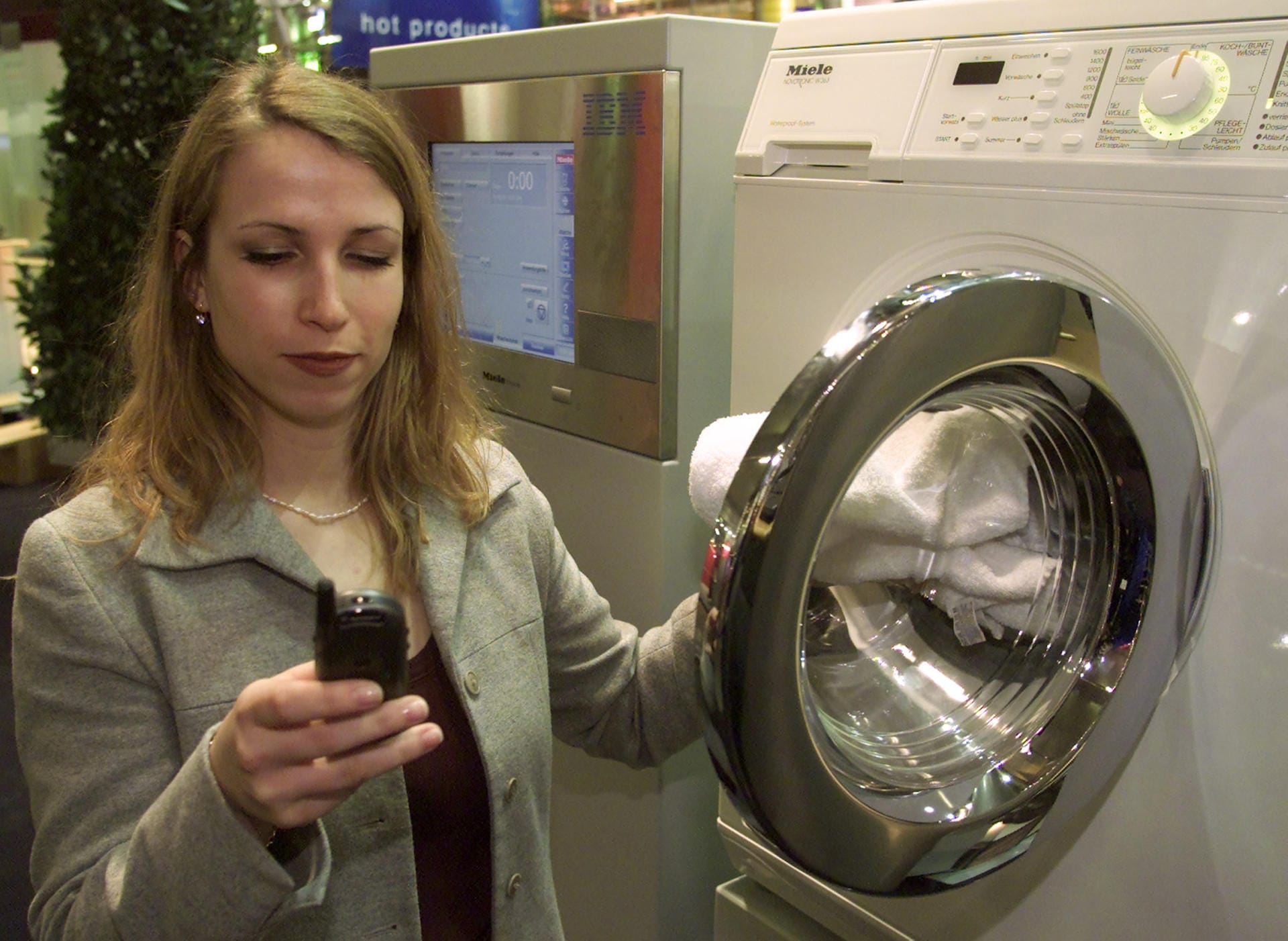 Cebit 2001: Eine Frau präsentiert eine intelligente Waschmaschine von Miele. Die Maschine ist mit dem Internet verbunden und schickt beispielsweise eine SMS, wenn sie repariert werden muss.