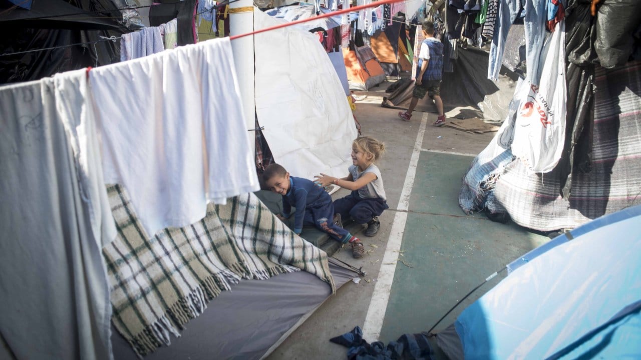 Kinder spielen zwischen Zelten und Wäscheleinen.