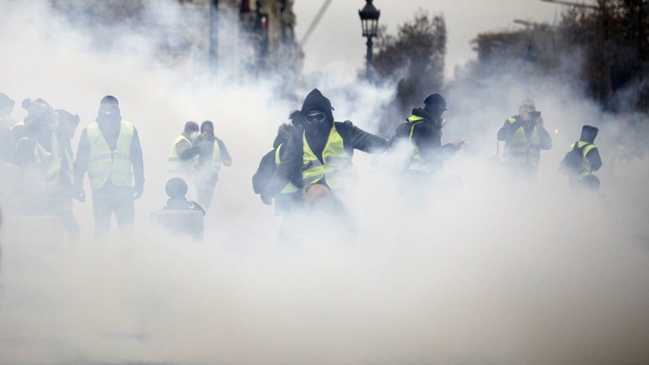 Maskierte "Gelbwesten" inmitten einer Tränengaswolke in der Nähe der Champs-Élysées.