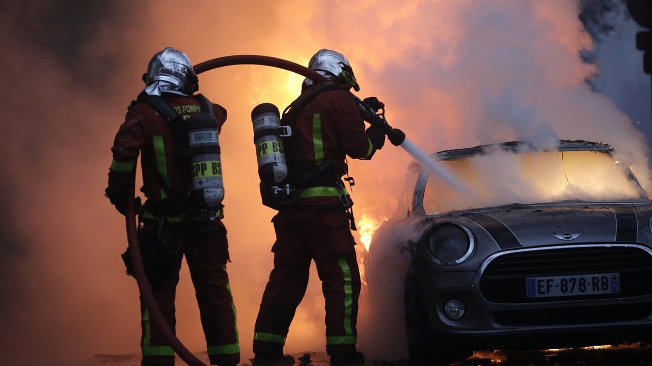 Feuerwehrleute löschen bei einem Protest der "Gelbwesten" in der Nähe der Champs-Elysees ein brennendes Auto.