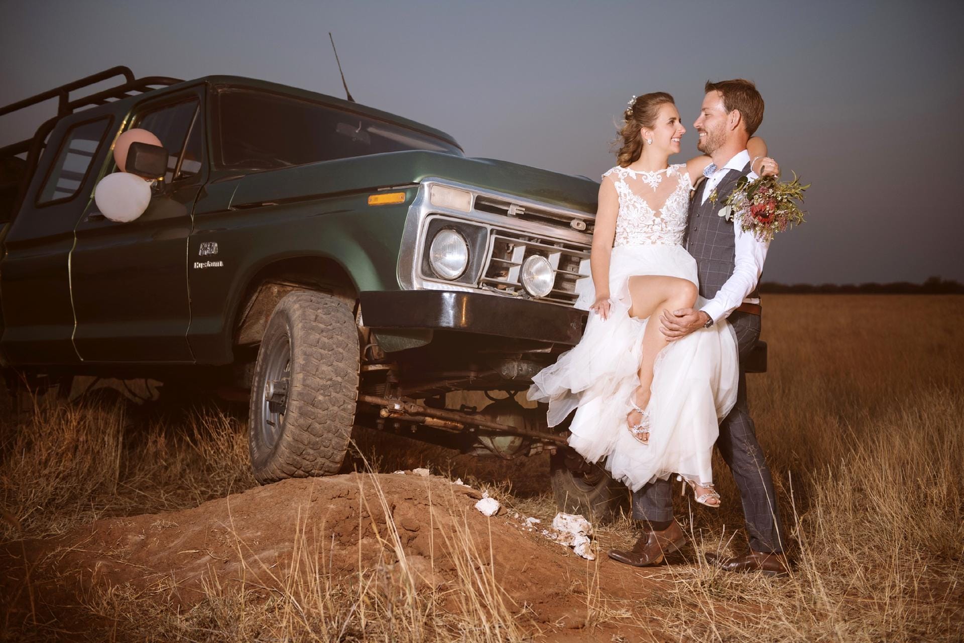 Ein etwas anderes Hochzeitsfoto: Anna und Gerald posieren in den Weiten Namibias vor einem Jeep.