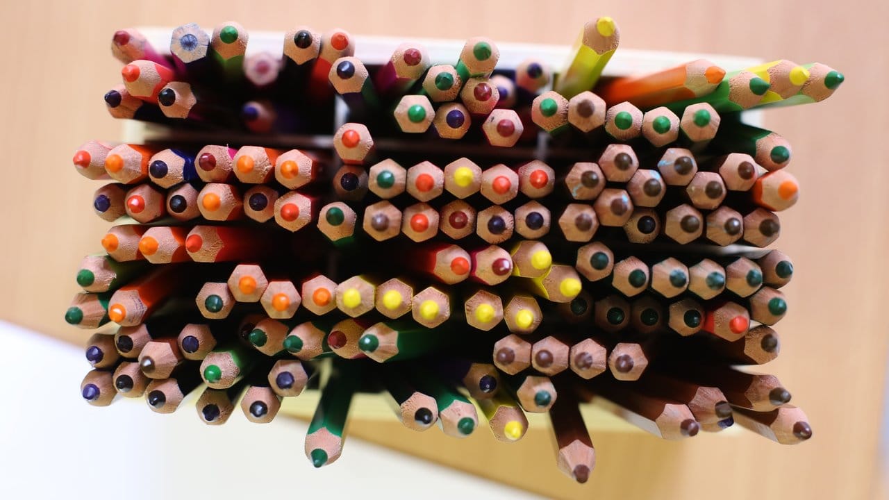 Verschiedenfarbige Buntstifte stehen in einer Kita auf einem Tisch.