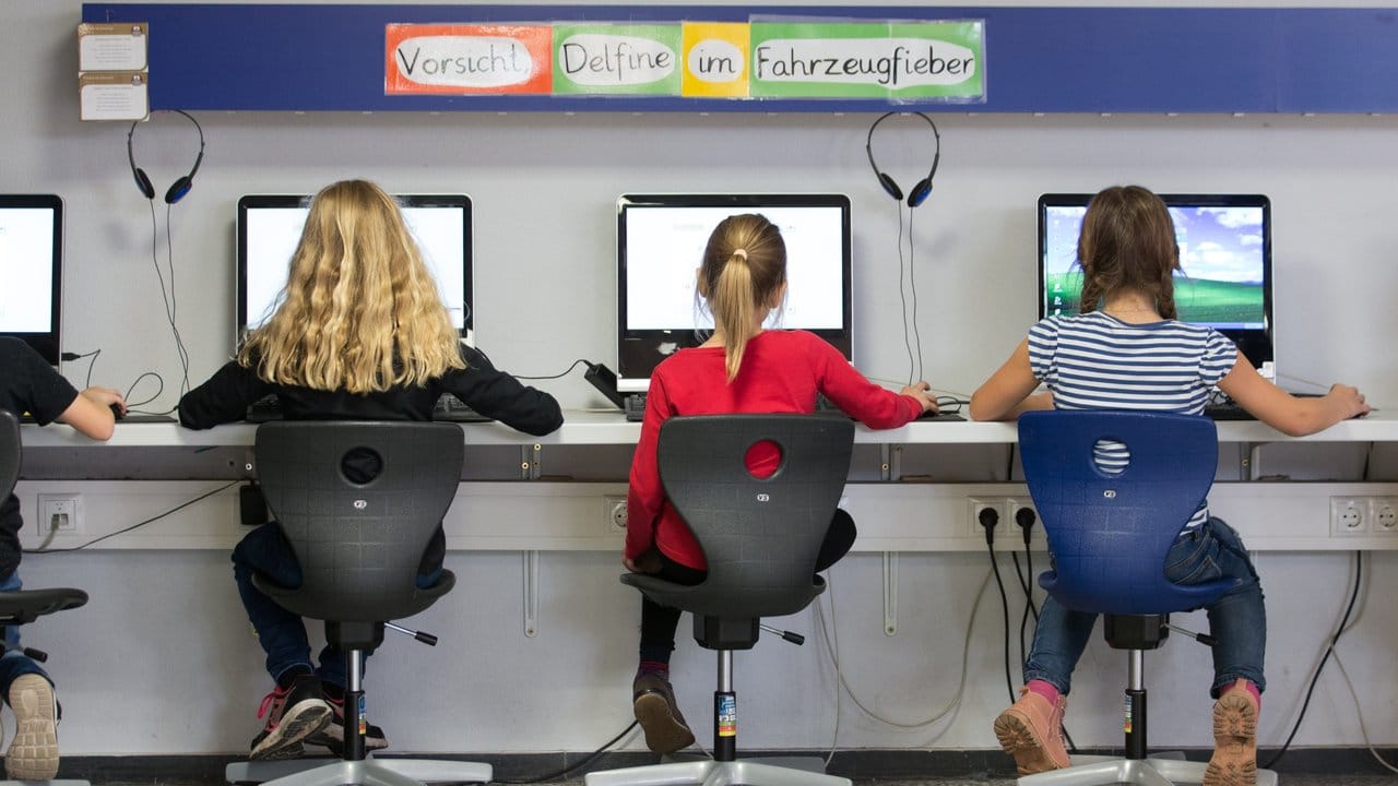 Schüler arbeiten in einem Klassenraum einer Grundschule an Computern.