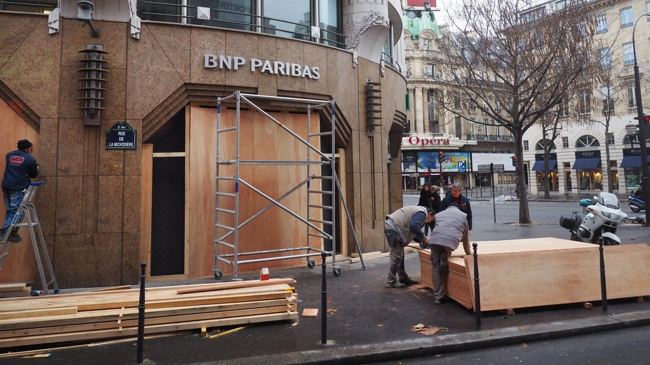 Handwerker sichern in Paris eine Bankfiliale in der Nähe der Oper mit Holzplatten.