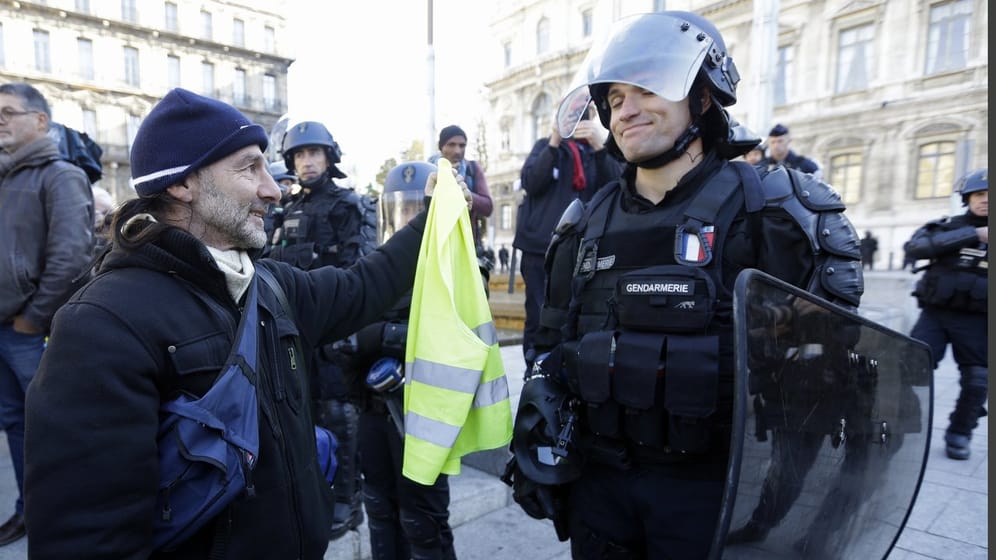 Entspannter Moment: Ein Demonstrant bietet einem Polizisten an, doch auch eine gelbe Warnweste zu nehmen.