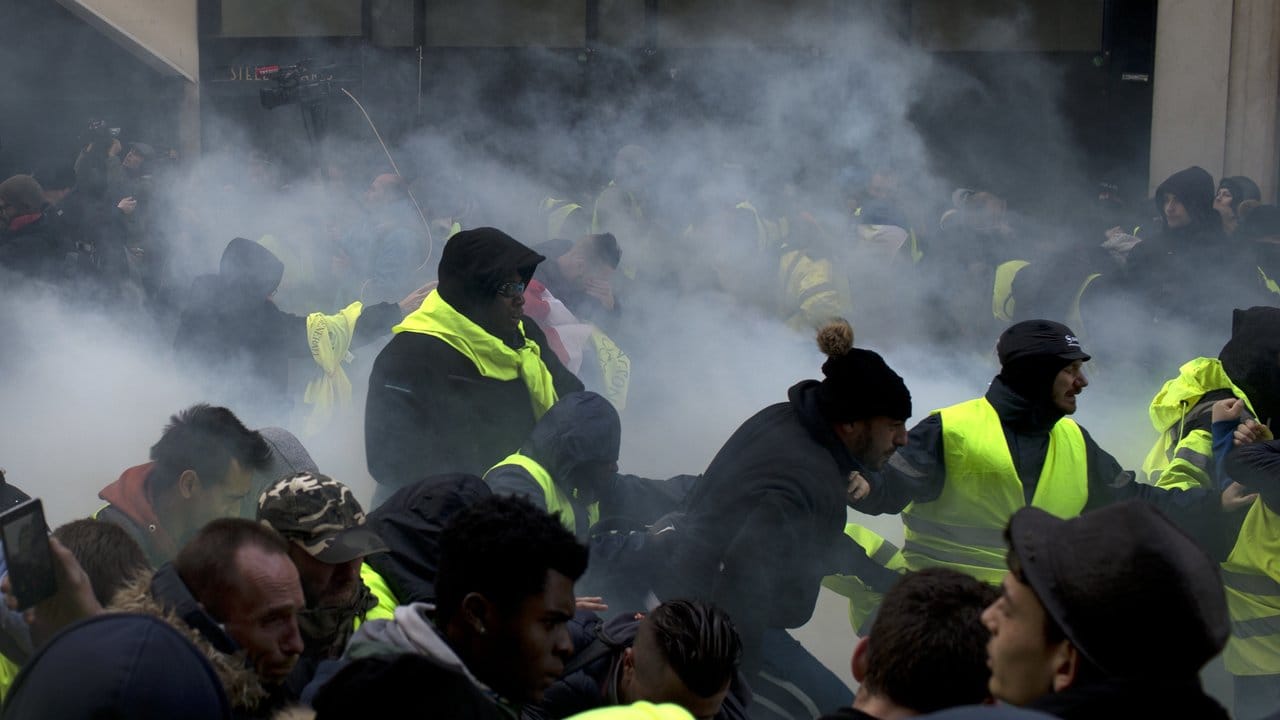 Zusammenstoß mit der Staatsmacht: Demonstranten rennen in Paris durch einen dichten Tränengasnebel.