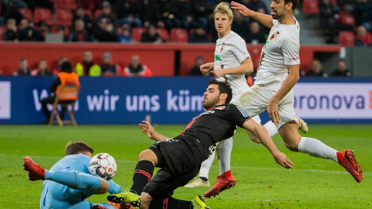 Augsburg-Keeper Andreas Luthe (l) versucht gegen Leverkusens Kevin Volland (M) zu klären.