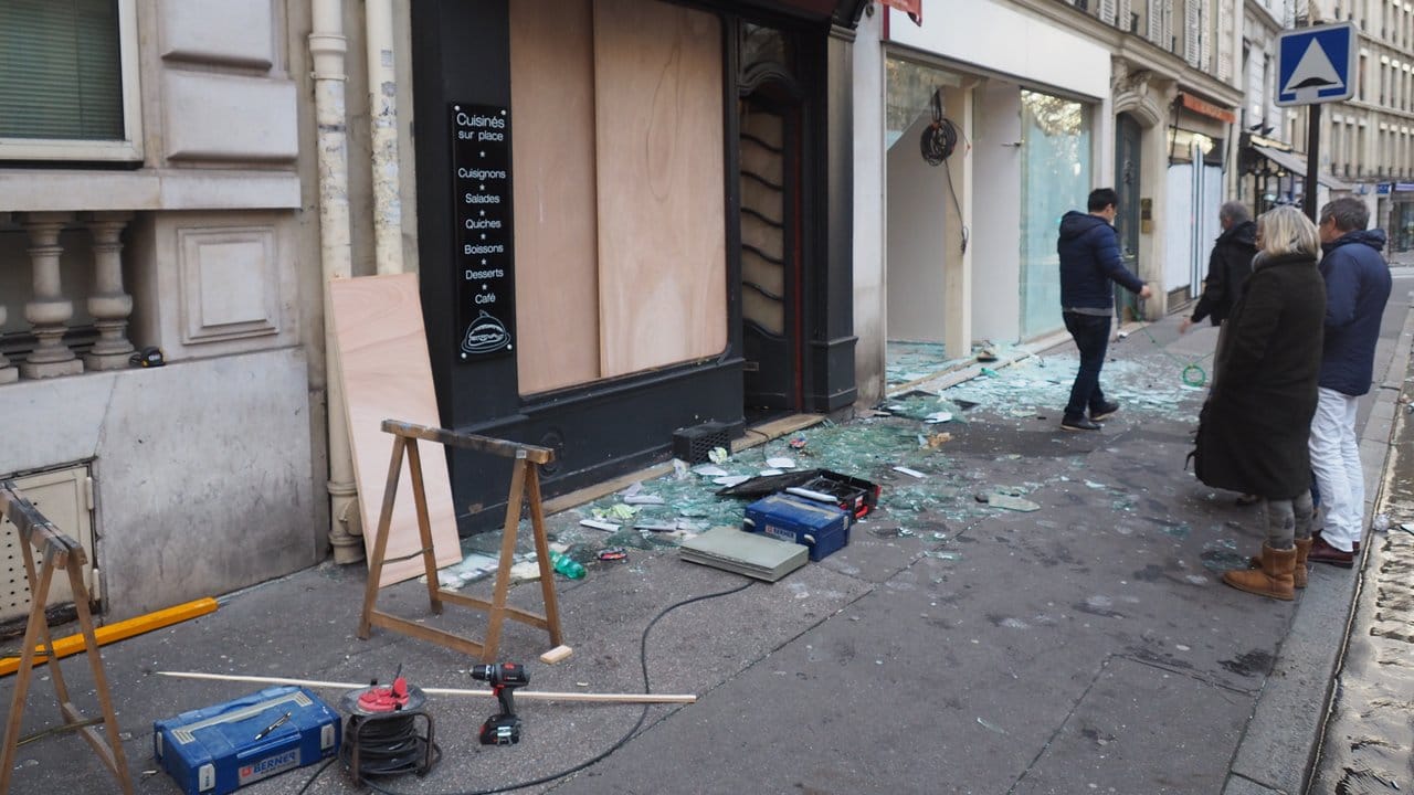 Passanten betrachten am Sonntagmorgen in Paris Zerstörungen an Schaufenstern im 8.