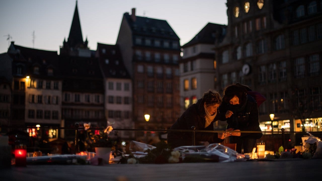 Passanten zünden nahe des Straßburger Weihnachtsmarkts eine Kerze an.