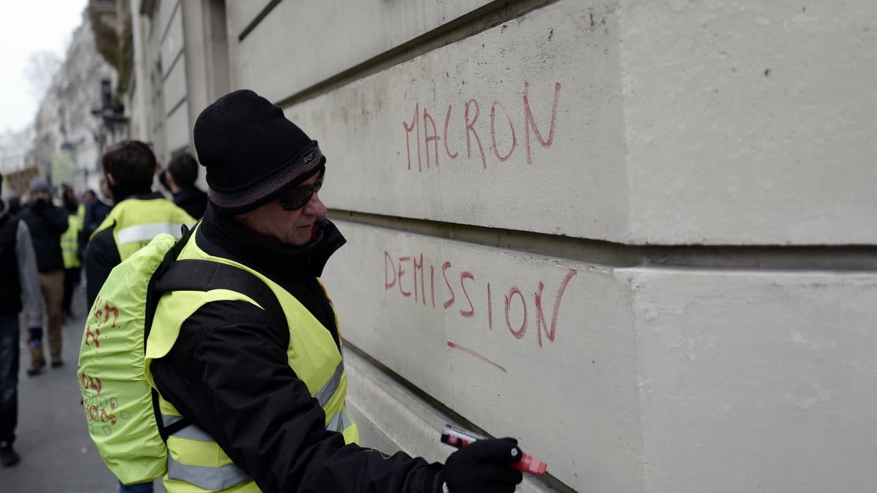 "Macron - Rücktritt": Ein Protestler schreibt auf eine Hauswand in Paris.