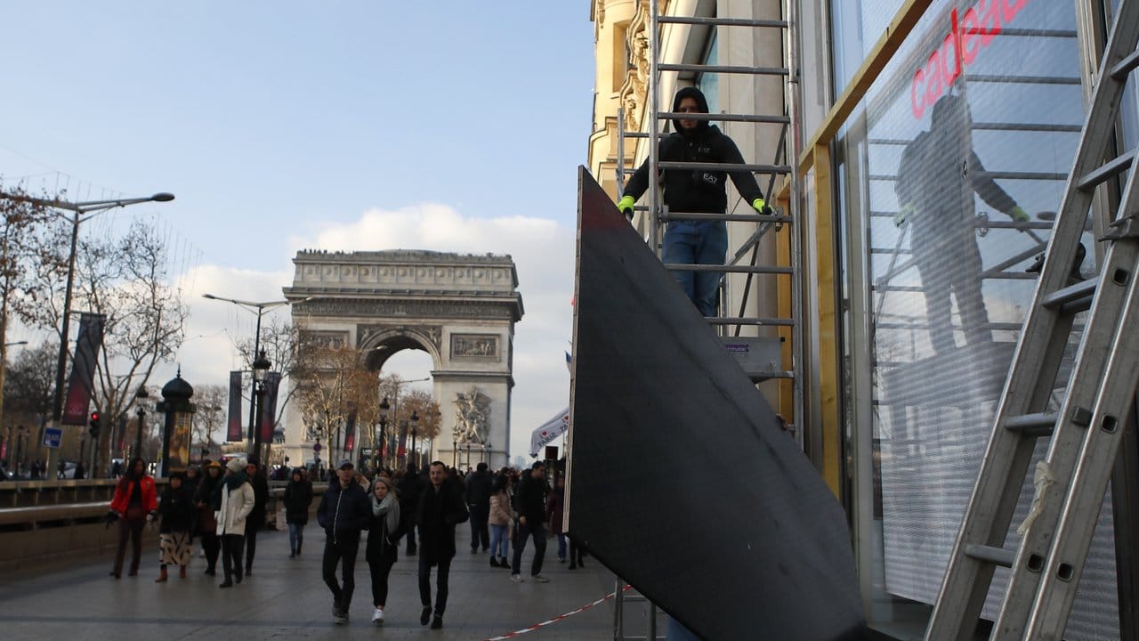 Ein Arbeiter montiert einen Schutz am Schaufenster eines Geschäfts in der Nähe des Arc de Triomphe in Paris.