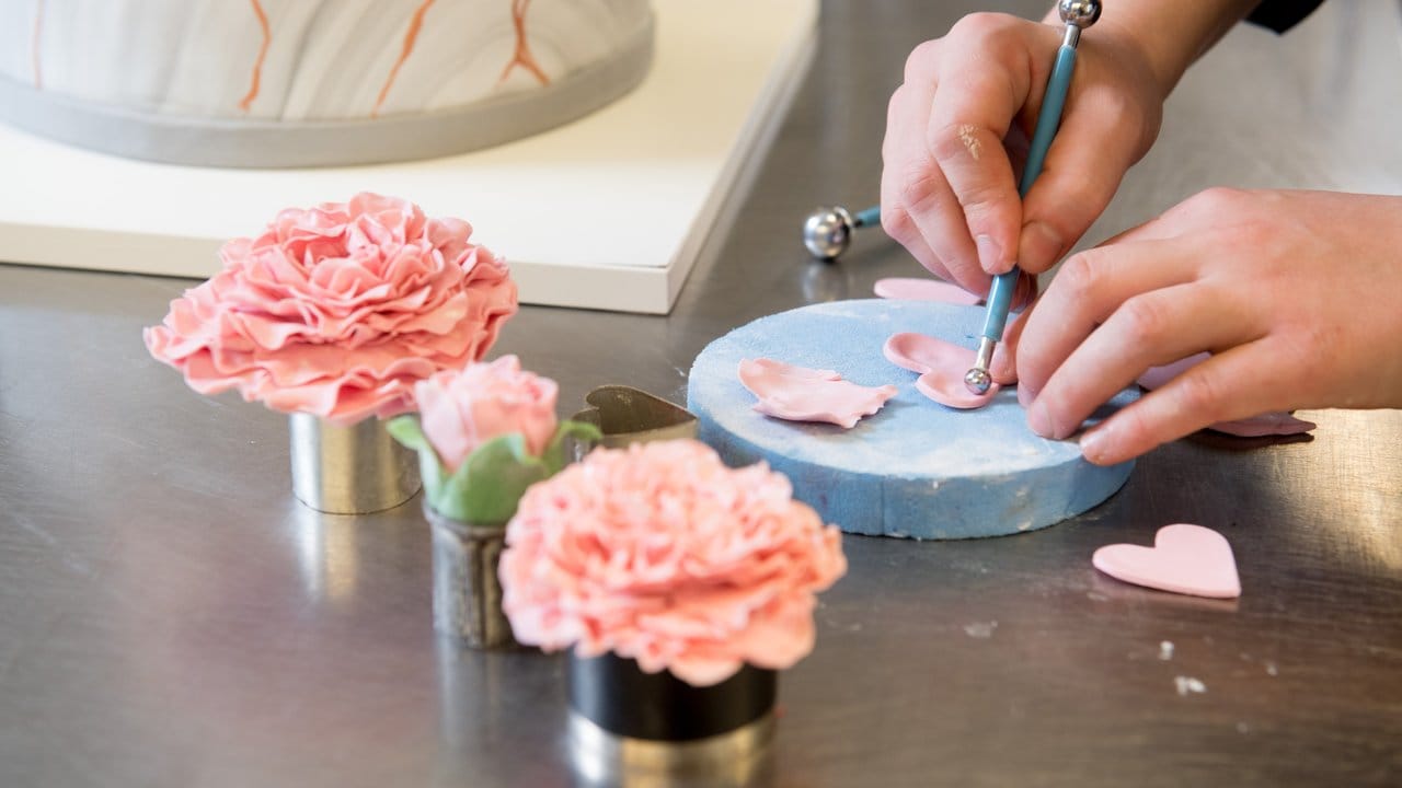 Eine kreative Ader und ästhetisches Empfinden sind Voraussetzungen: Mit raffinierten Rosenblättern aus Modellierschokolade wird etwa eine Hochzeitstorte zum Blickfang.