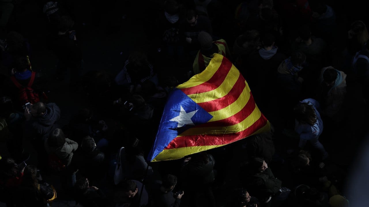 Demonstranten schwenken die Flagge Kataloniens.