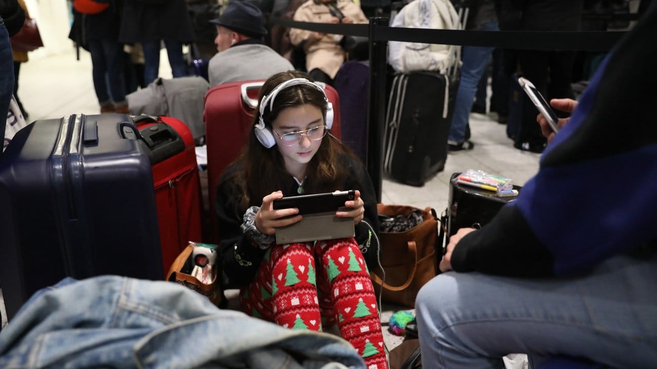 Sie macht das Beste daraus: Ein Mädchen verbringt die Wartezeit am Flughafen Gatwick unter Kopfhörern.