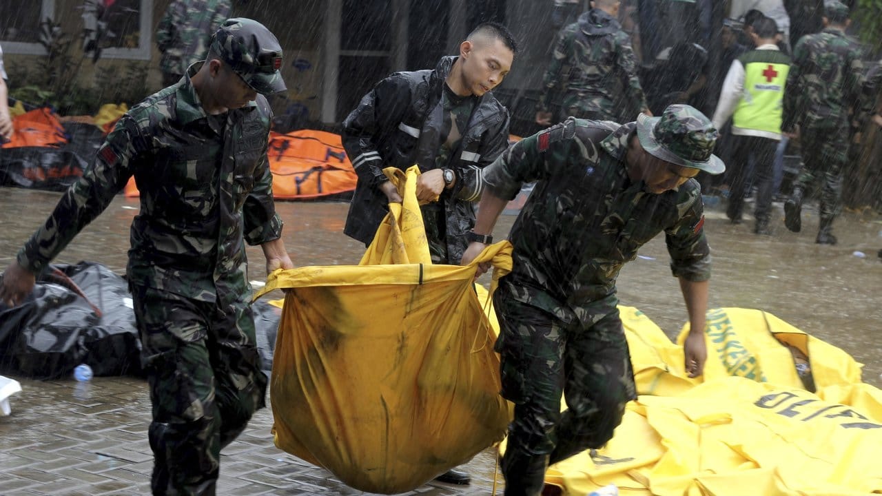 Indonesische Soldaten tragen einen Leichensack mit einem Tsunami-Opfer.