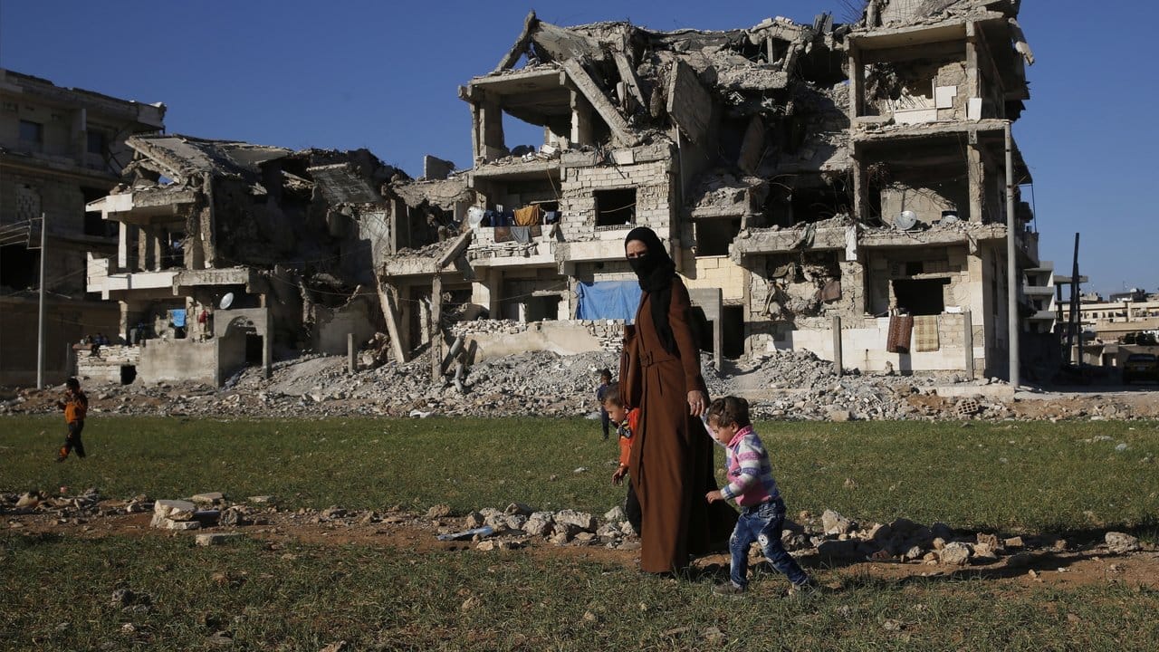 Eine Syrerin in Manbidsch vor bei Kämpfen mit dem IS zerstörten Gebäuden.