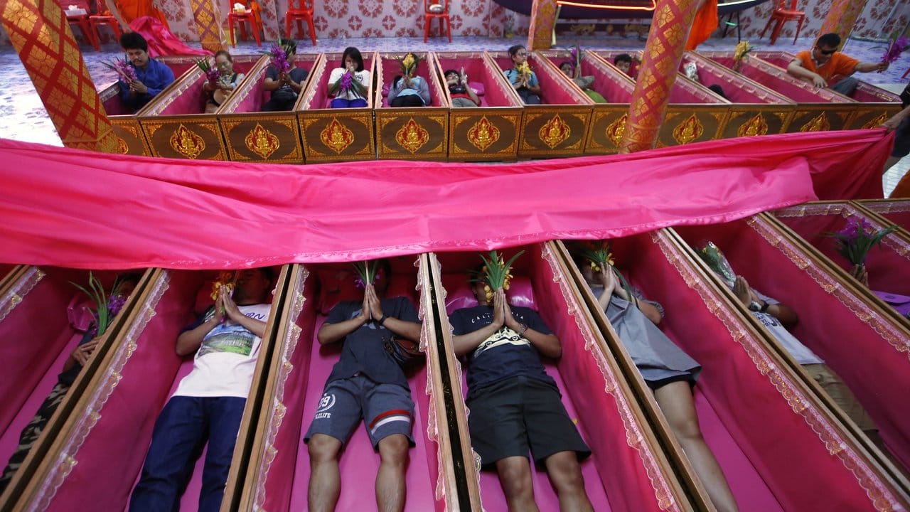 Gläubige liegen in rosa Särgen und beten während einer Zeremonie, die Tod und Wiedergeburt symbolisiert - und von Unglück befreit.