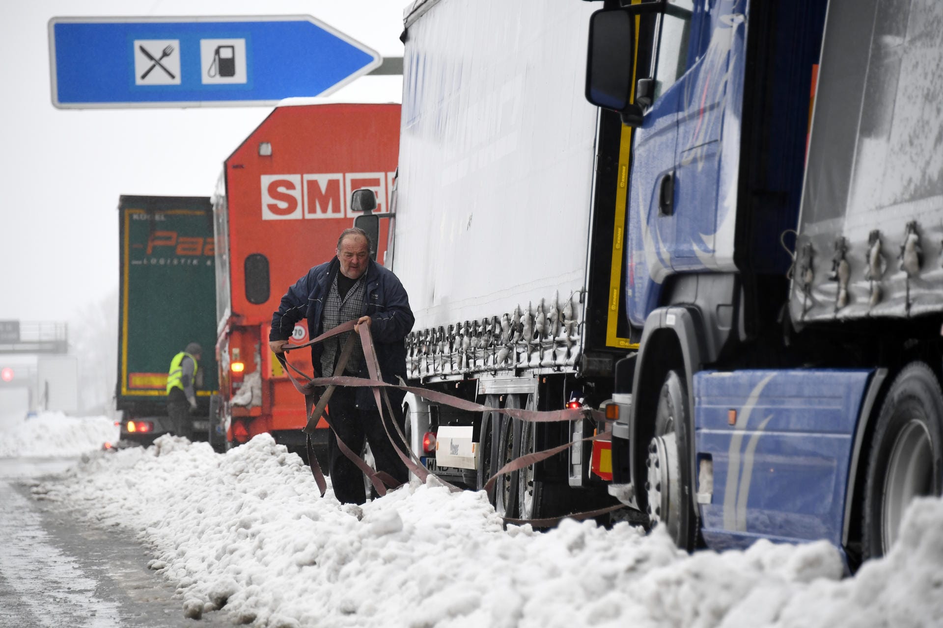 Bei Holzkirchen in Bayern versuchen LKW-Fahrer an der A8 ihre feststeckenden Fahrzeuge aus dem Schnee zu befreien.