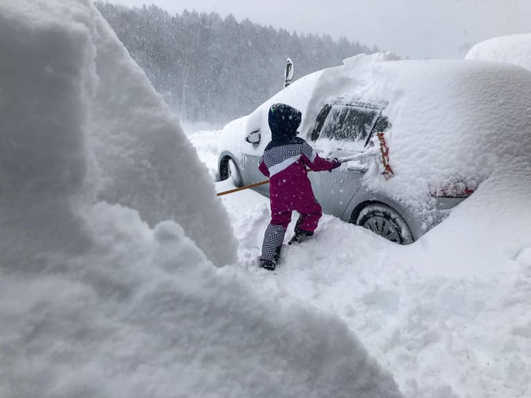 Ein Kind befreit im österreichischen Henndorf ein Auto vom Schnee.