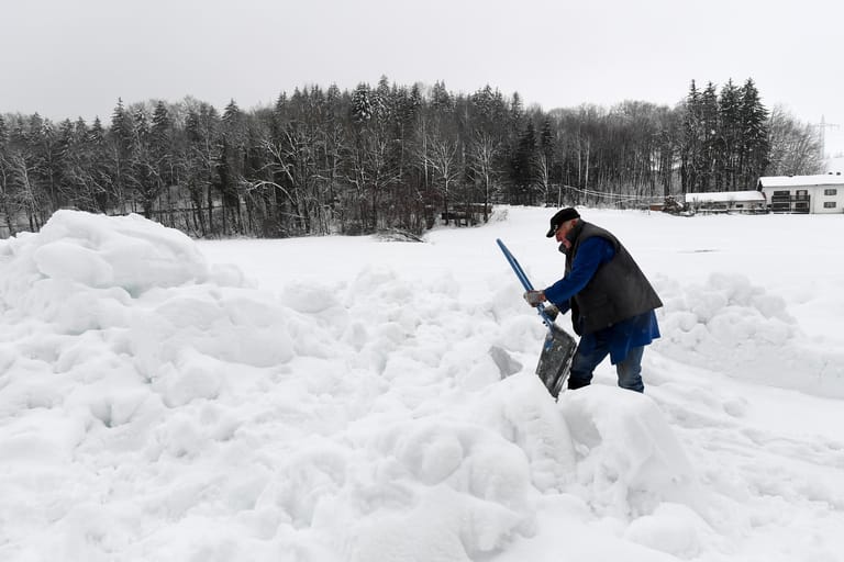 Ein Mann räumt im bayerischen Traunstein Schnee.