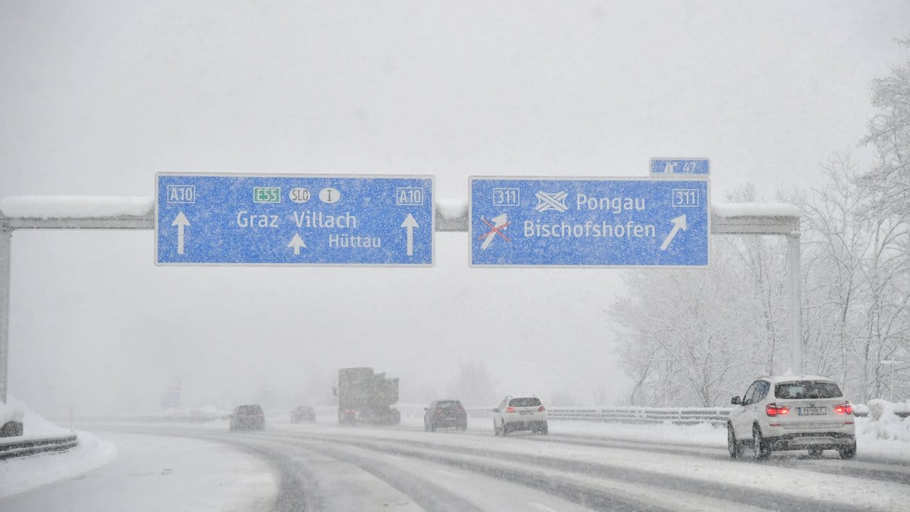 Autos sind bei Salzburg auf der verschneiten Autobahn unterwegs.