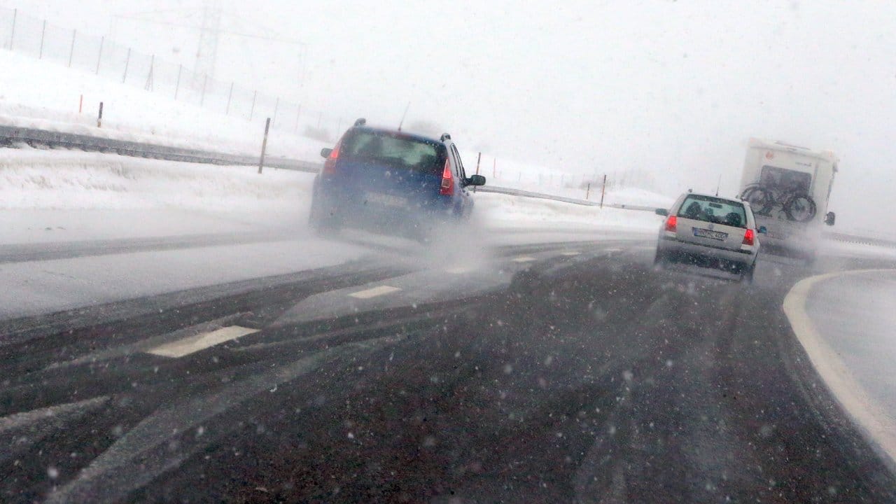 Autos fahren auf der A7 im Schneetreiben.