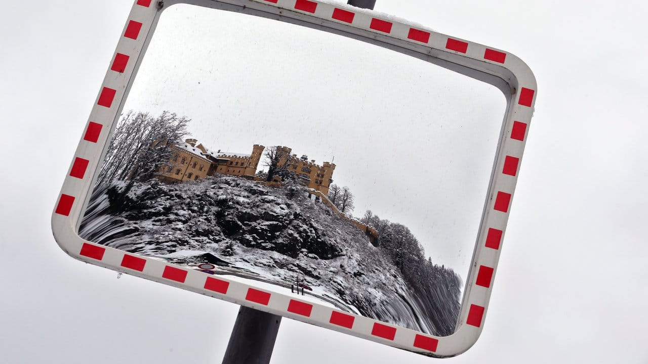 Das in winterlicher Umgebung stehende Schloss Hohenschwangau ist in einem Verkehrsspiegel zu sehen.