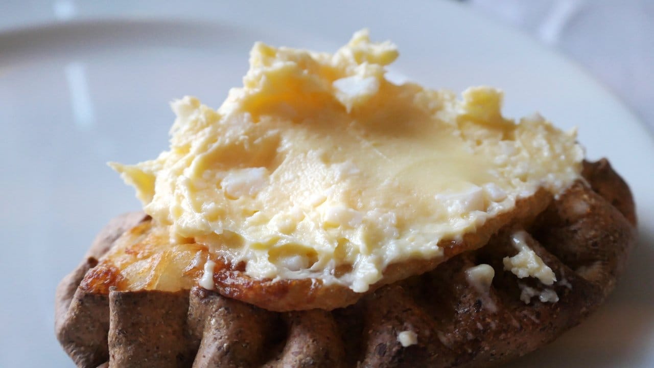 Eine Creme aus hartgekochten Eiern und Butter wird am Tisch auf die Pirogge gestrichen.