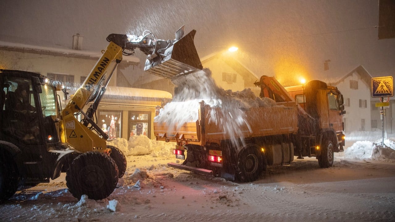 Ein Radlader lädt in der Innenstadt von Miesbach zusammengeschobenen Schnee auf einen LKW.