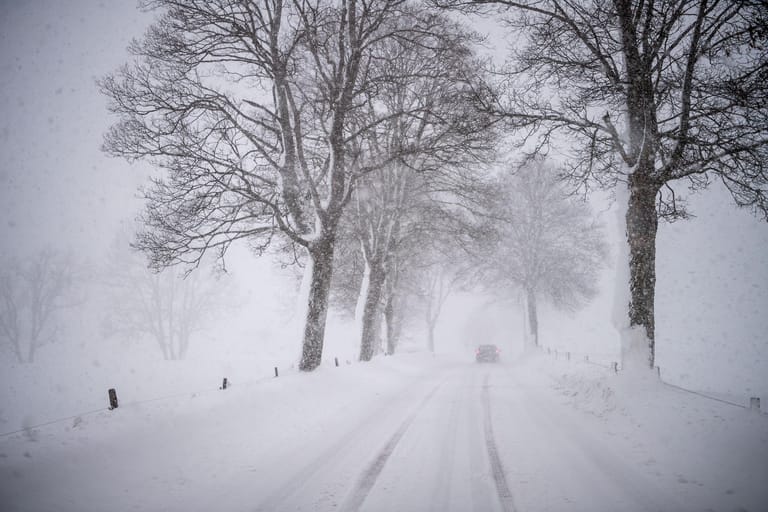 Ein Auto fährt über eine verschneite Landstraße bei Warngau in Bayern.