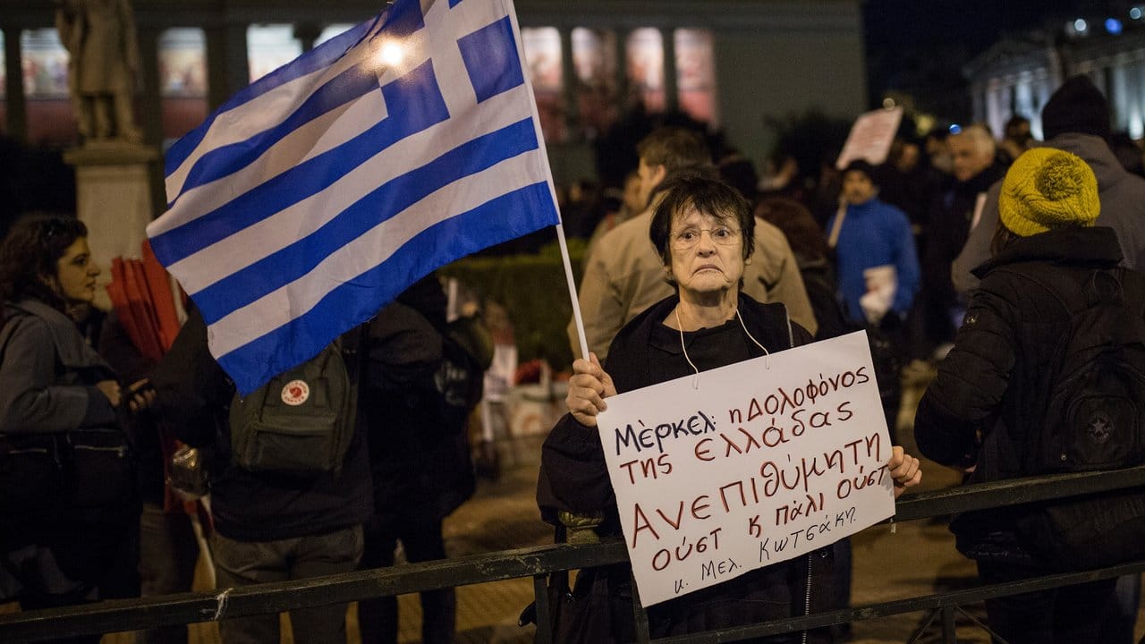 Eine Frau hält aus Protest gegen den Besuch von Bundeskanzlerin Merkel ein Schild mit der Aufschrift "Merkel, die Mörderin Griechenlands - unerwünscht".