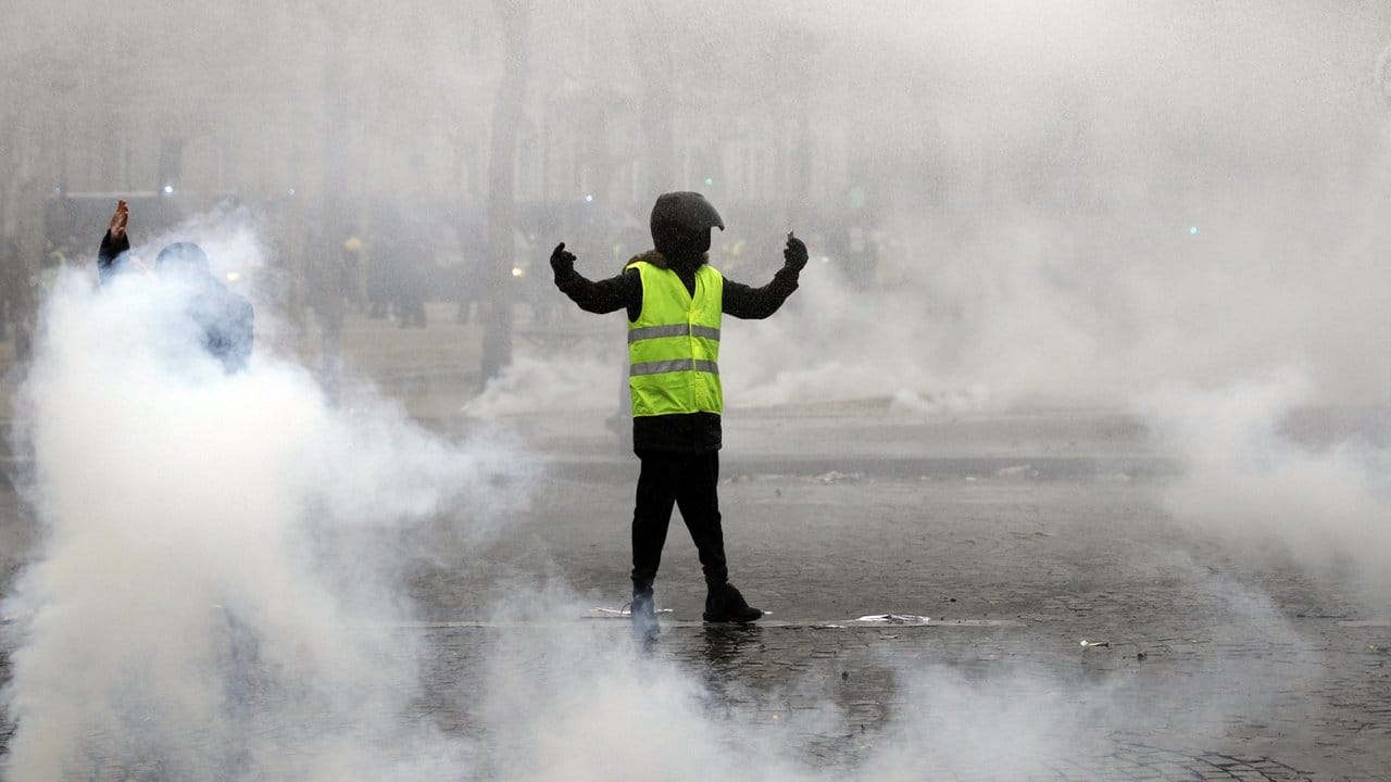 Ein Demonstrant in gelber Weste steht in Paris inmitten von Rauchschwaden.