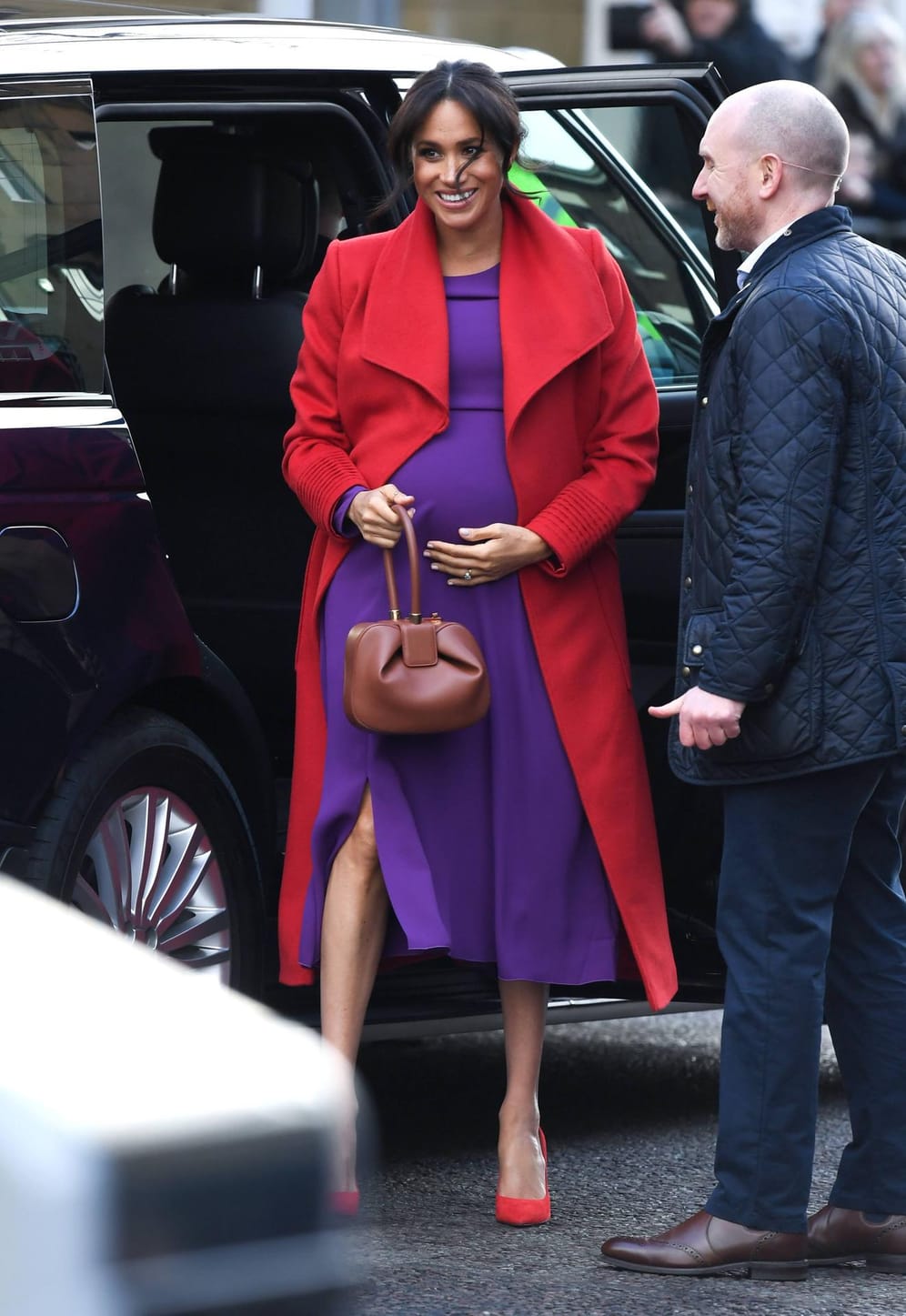 14. Januar 2019: Herzogin Meghan besucht mit Prinz Harry die Stadt Birkenhead nahe Liverpool. Ihren Babybauch, der in einem Kleid in knalligem Lila steckt, berührt sie immer wieder liebevoll. Den Colourblocking-Look perfektioniert sie durch einen Mantel in knalligem Rot.