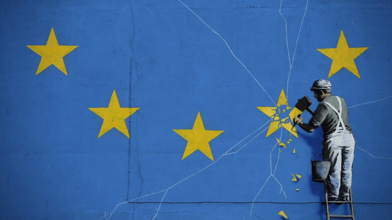 So sieht es der wohl bekannteste unbekannte Künstler der Welt: Das Brexit-Wandbild von Banksy zeigt einen Mann, der einen Stern aus der EU-Flagge heraushämmert.