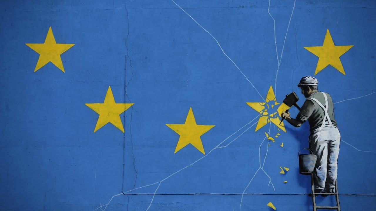 So sieht es der wohl bekannteste unbekannte Künstler der Welt: Das Brexit-Wandbild von Banksy zeigt einen Mann, der einen Stern aus der EU-Flagge heraushämmert. So sieht es der wohl bekannteste unbekannte Künstler der Welt: Das Brexit-Wandbild von Banksy zeigt einen Mann, der einen Stern aus der EU-Flagge heraushämmert.